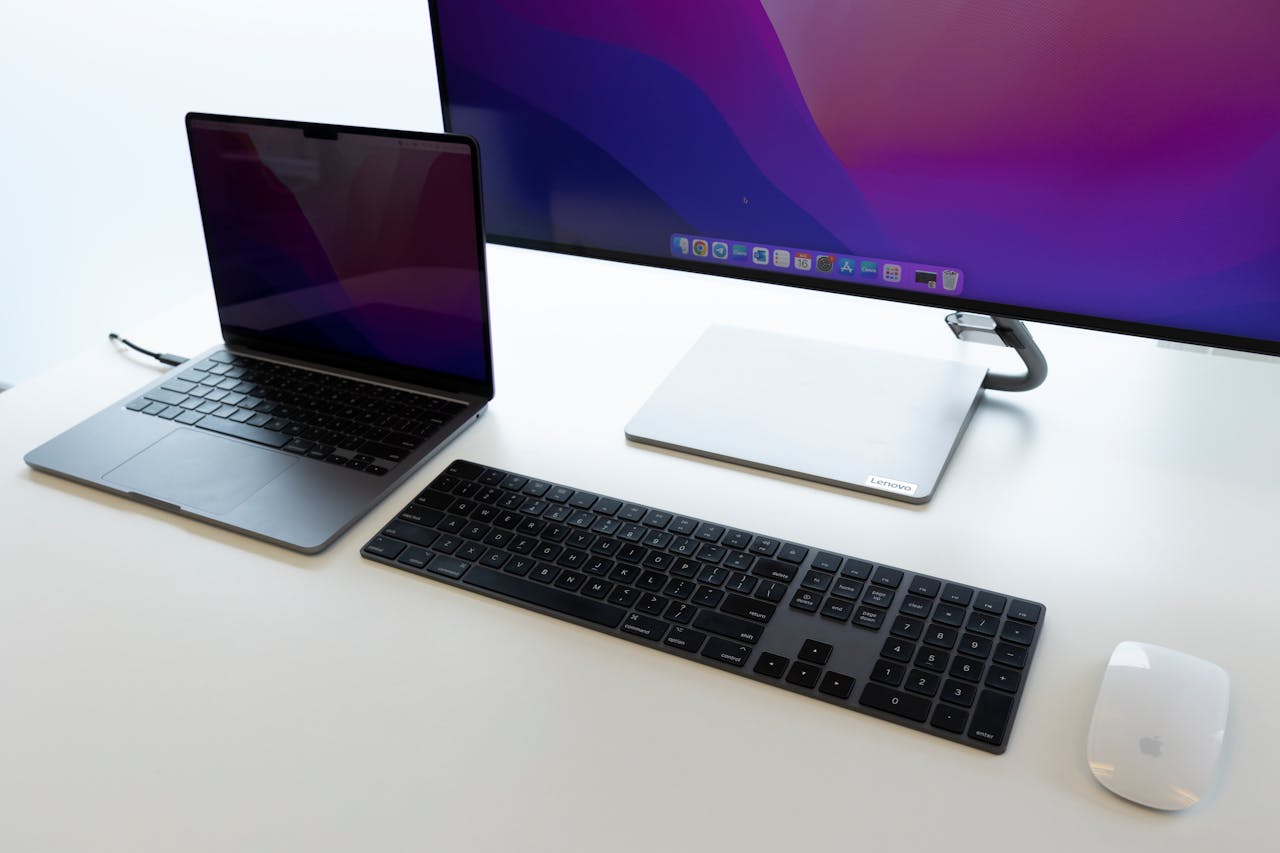 Sleek office desk setup with laptop, keyboard, and monitor for productive work environment.